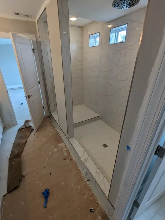 Marble-look tile walk-in shower with bench and herringbone floor